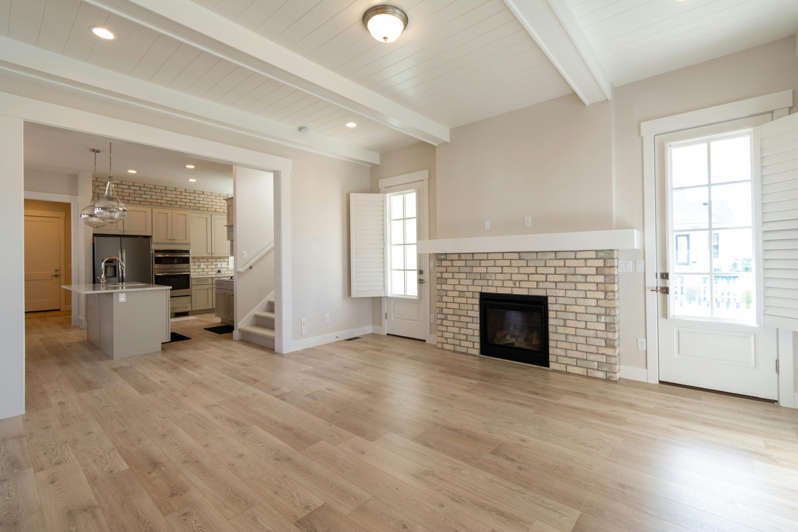 Bright and airy modern living space featuring a brick fireplace and open kitchen design.